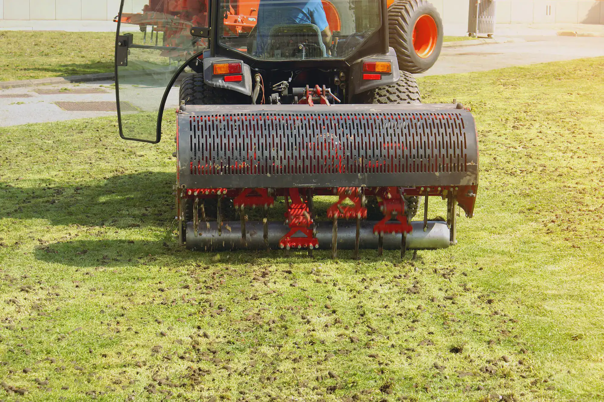 A tractor aerates a Suffolk County lawn, leaving soil plugs behind as part of effective lawn renovation.