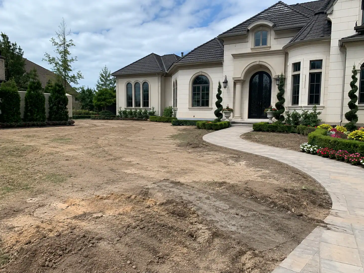 A large luxury house in Suffolk County, NY features a curved walkway, neat hedges, and lawn-ready yard.